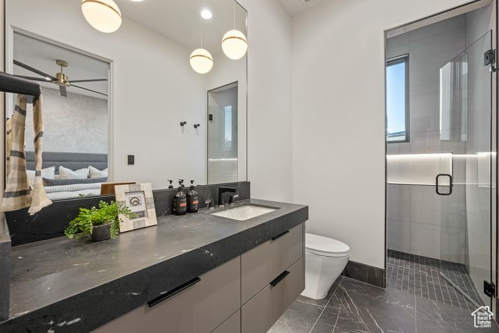 Bathroom with toilet, vanity, an enclosed shower, and ceiling fan