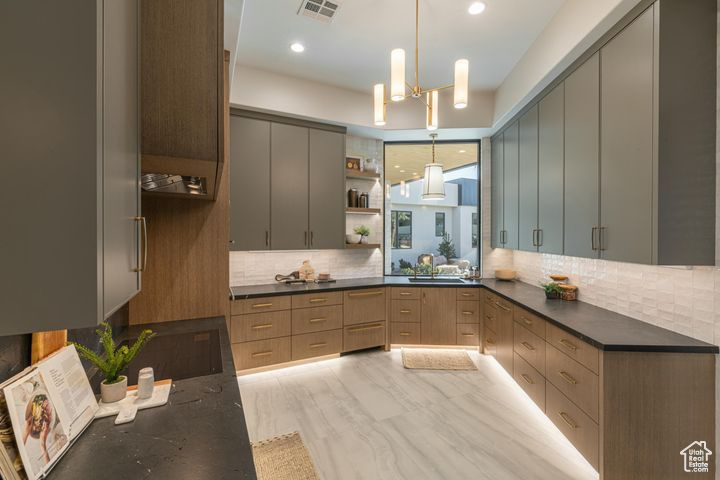 Kitchen featuring light brown cabinetry, pendant lighting, gray cabinetry, and decorative backsplash