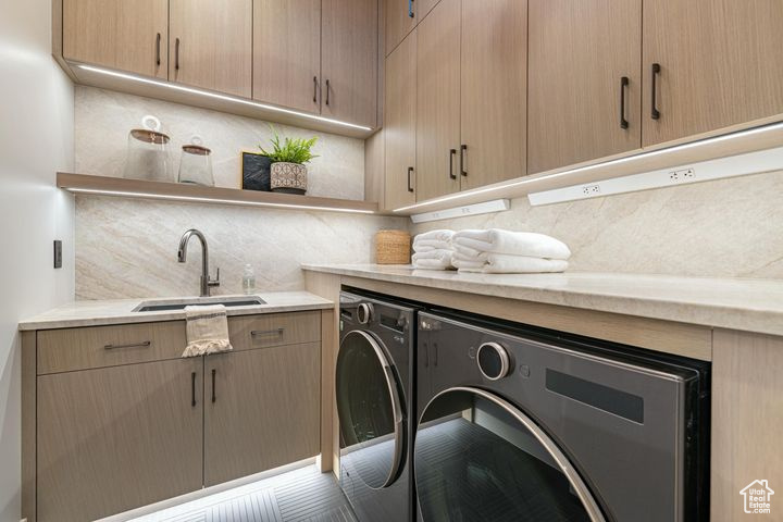 Laundry room with washing machine and dryer, sink, and cabinets