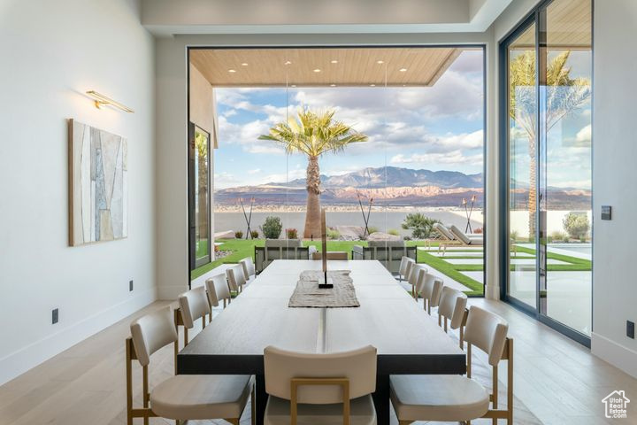 Dining space with a mountain view, expansive windows, light wood-type flooring, and a healthy amount of sunlight