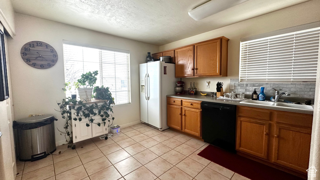 Kitchen featuring white refrigerator with ice dispenser, brown cabinets, light countertops, a sink, and dishwasher