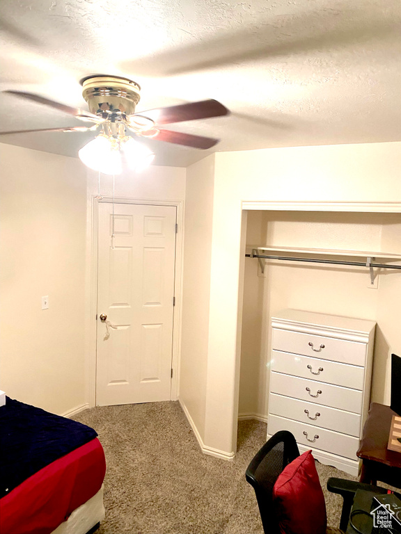 Carpeted bedroom featuring ceiling fan, a textured ceiling, baseboards, and a closet