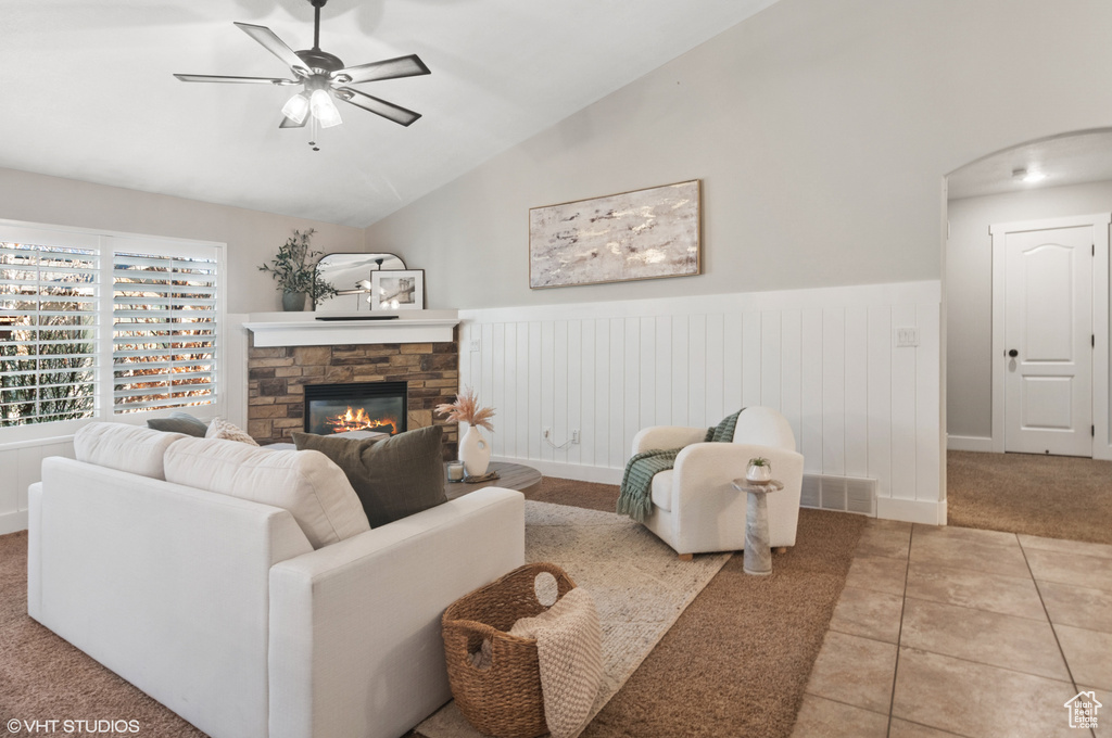 Living area featuring vaulted ceiling, a fireplace, tile patterned floors, and wainscoting