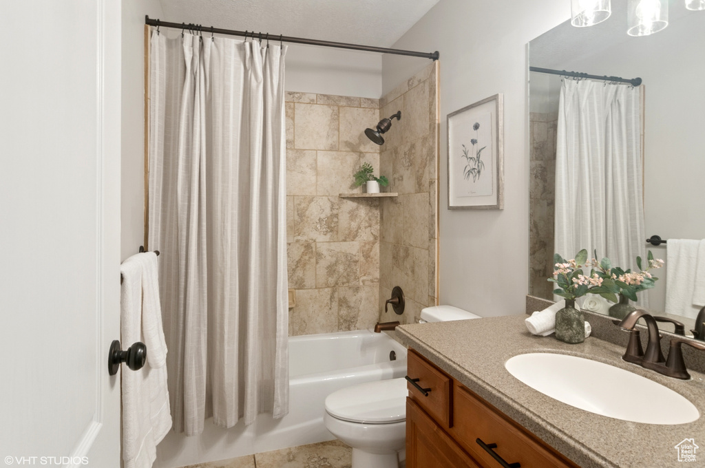 Full bath with vanity, toilet, and shower / bath combo with shower curtain