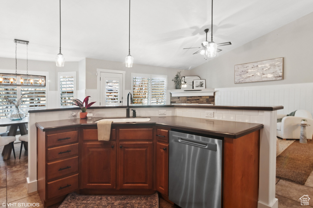 Kitchen featuring a sink, stainless steel dishwasher, dark countertops, open floor plan, and a wealth of natural light