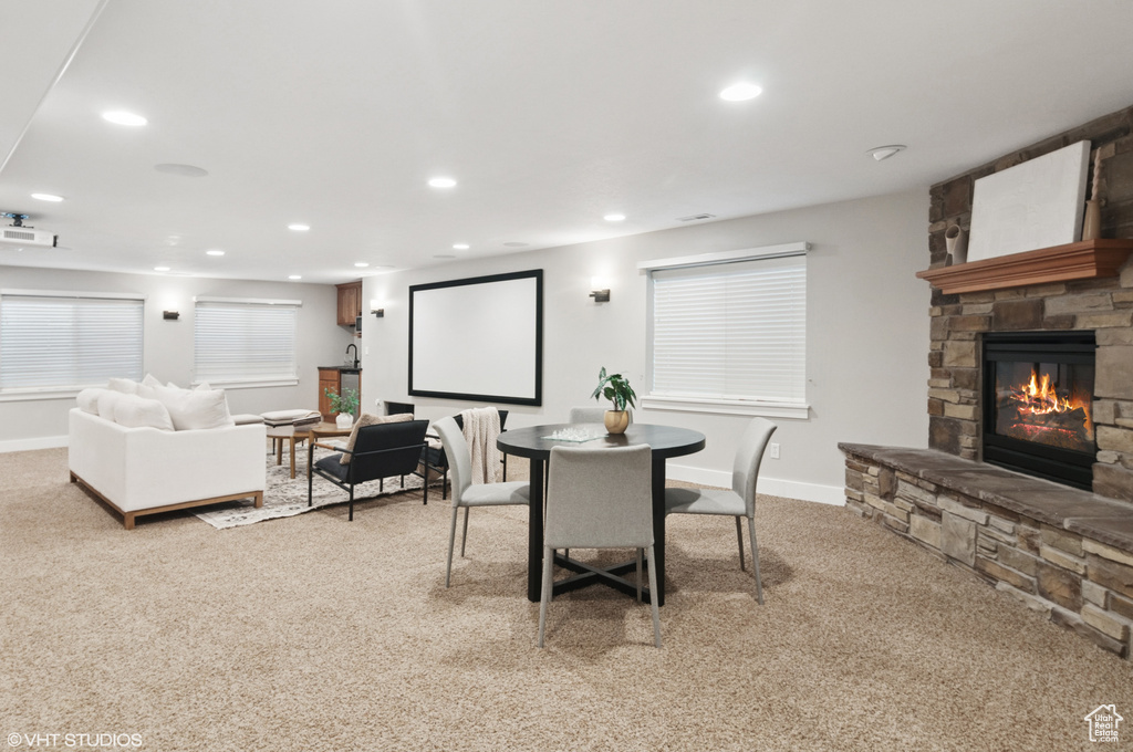 Dining room with light carpet, a stone fireplace, recessed lighting, and baseboards