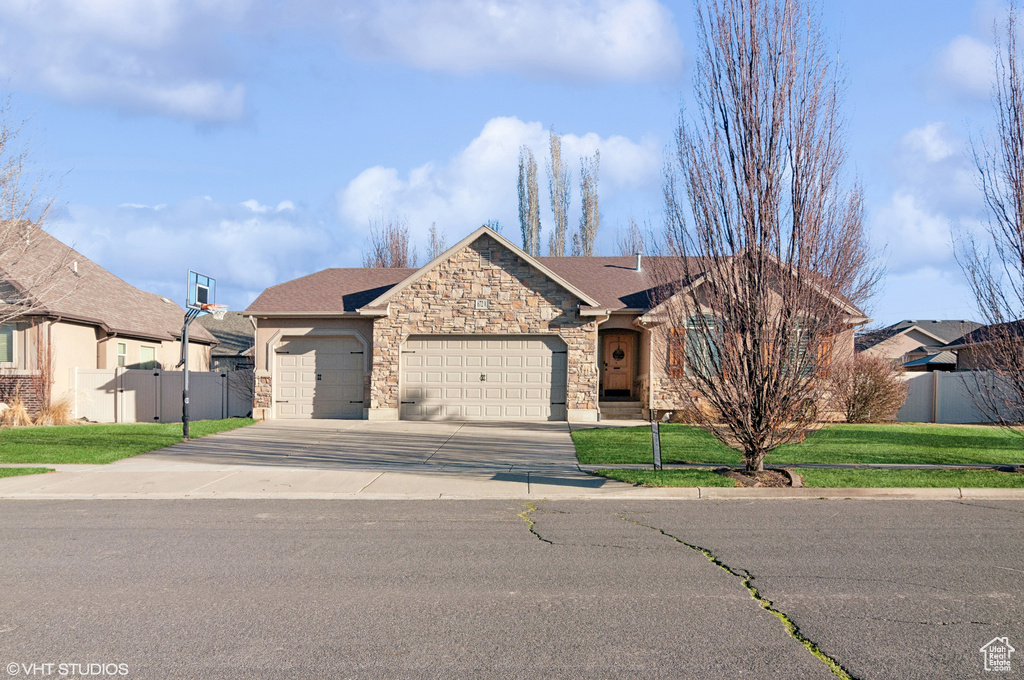 Single story home with fence, concrete driveway, a front yard, stone siding, and an attached garage