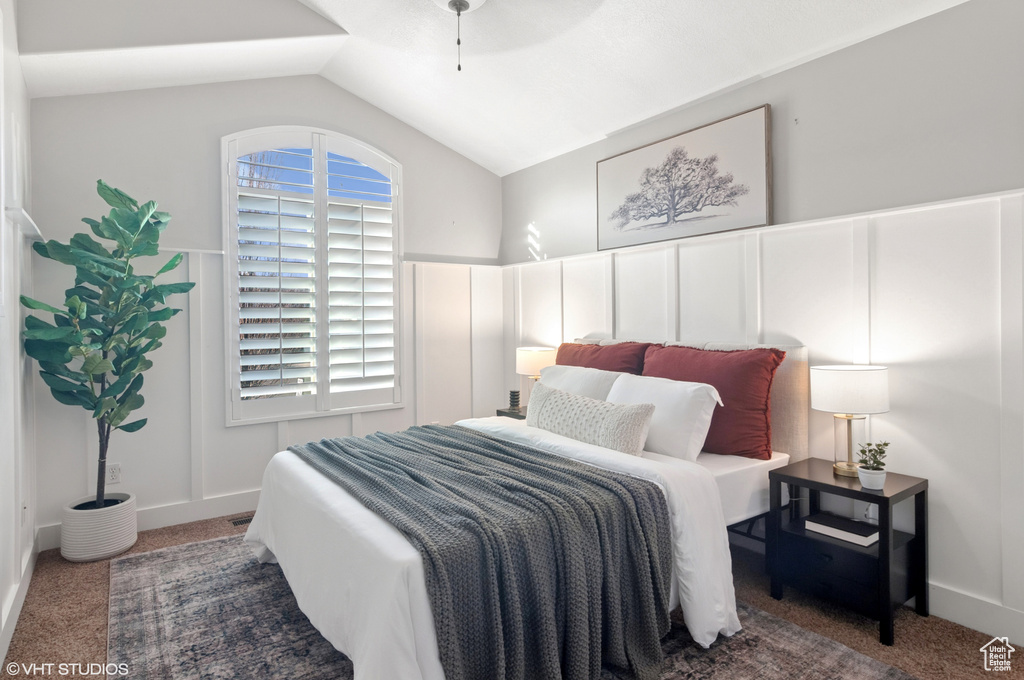 Carpeted bedroom featuring lofted ceiling and a ceiling fan