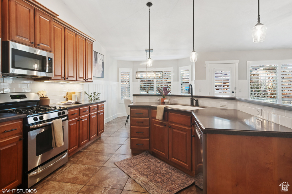 Kitchen featuring a sink, decorative backsplash, dark countertops, and appliances with stainless steel finishes