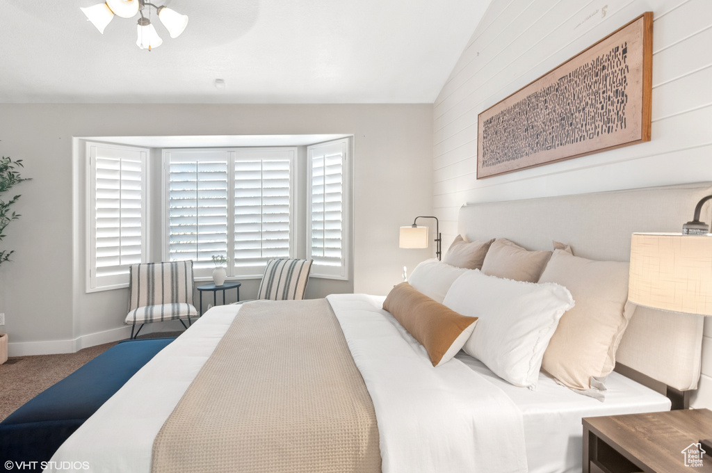 Carpeted bedroom with baseboards and vaulted ceiling