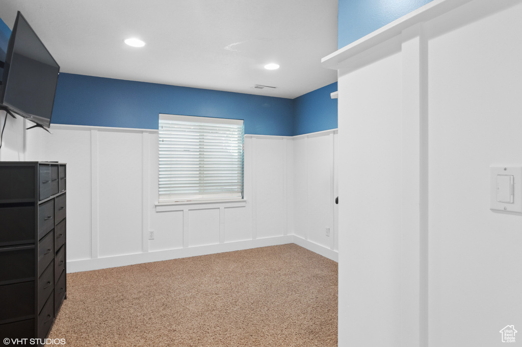 Interior space featuring a decorative wall, recessed lighting, visible vents, and carpet