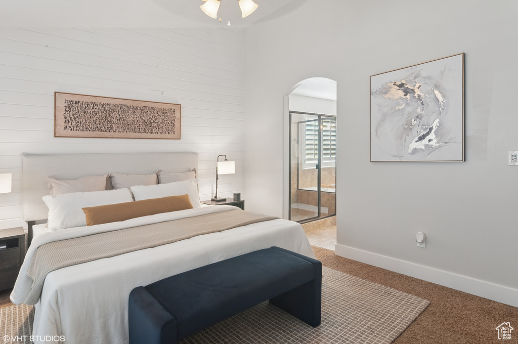 Bedroom featuring baseboards, arched walkways, light carpet, and ensuite bathroom