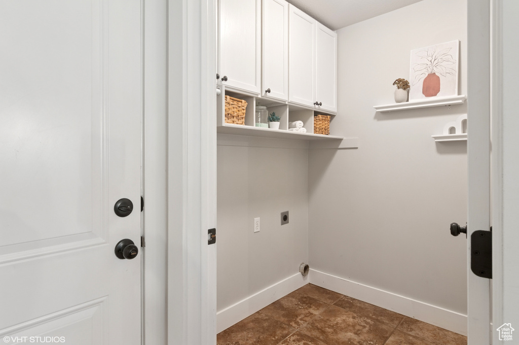 Clothes washing area featuring cabinet space, baseboards, and hookup for an electric dryer