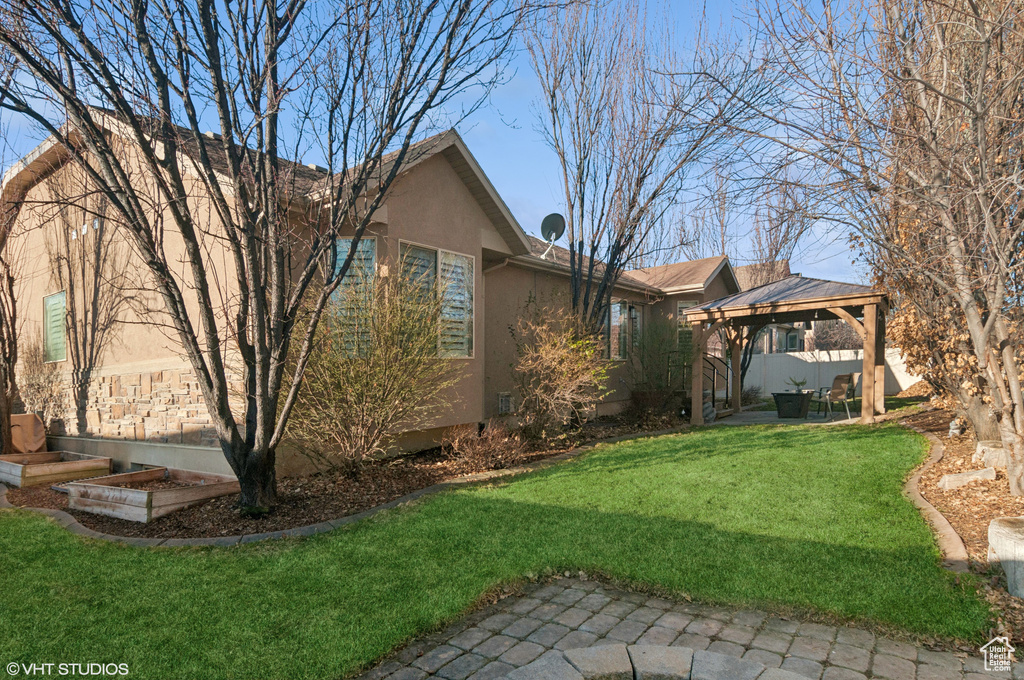 Exterior space featuring a gazebo, stucco siding, a patio, and a yard