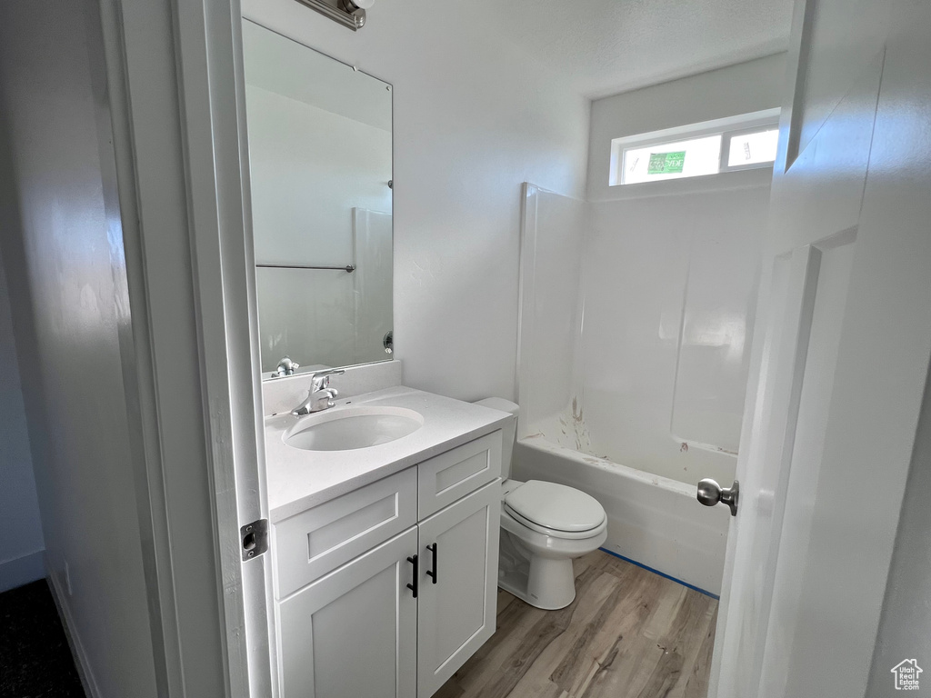Full bathroom with  shower combination, toilet, vanity, and wood-type flooring