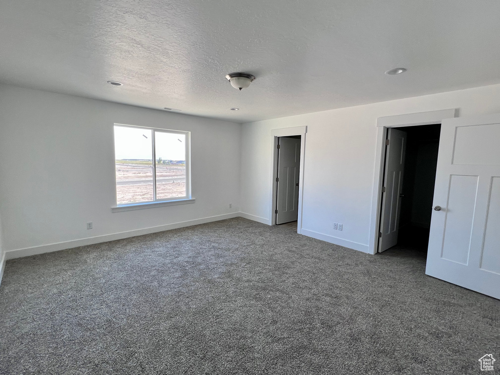 Unfurnished bedroom featuring a textured ceiling and carpet flooring