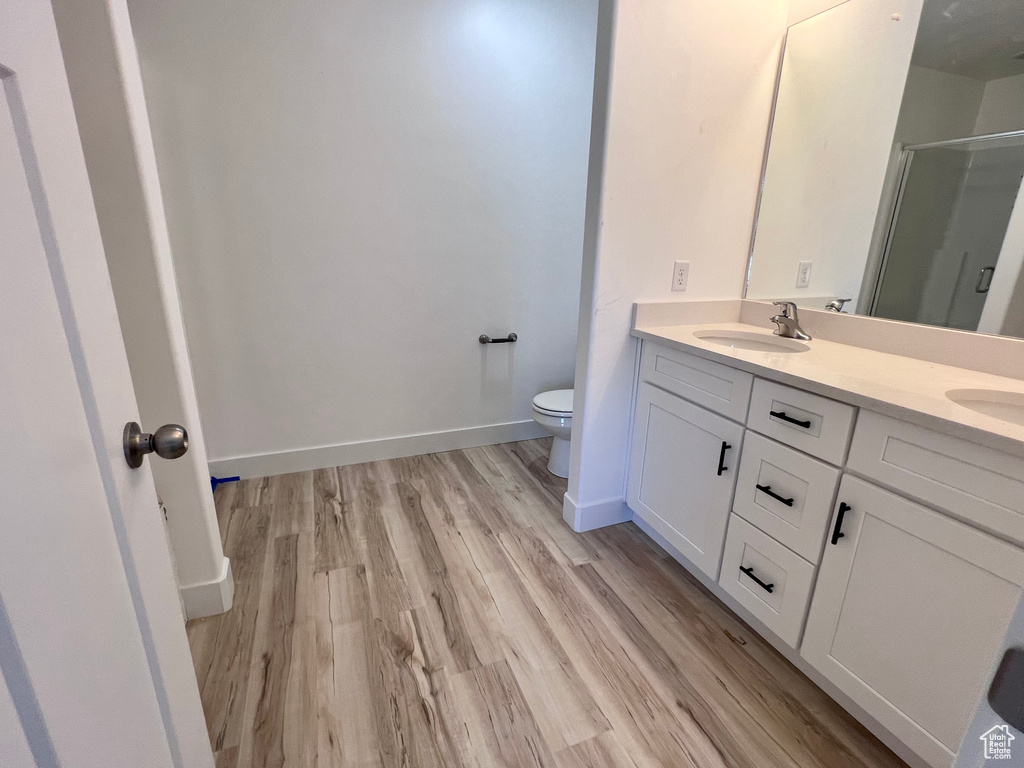 Bathroom with vanity, a shower with door, toilet, and hardwood / wood-style floors