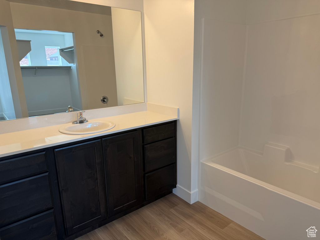 Full bathroom with wood finished floors, vanity, bathtub / shower combination, and baseboards