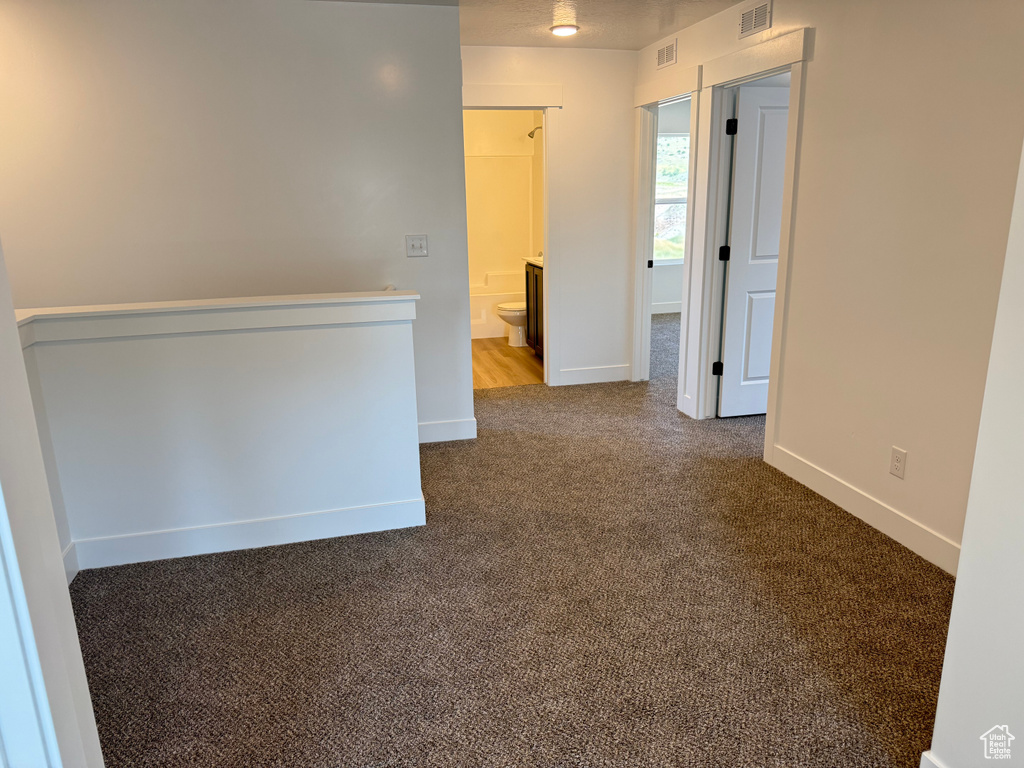 Unfurnished room with dark carpet and baseboards