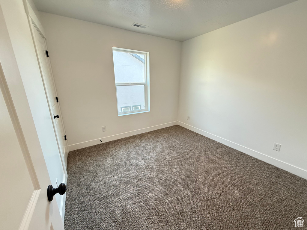 Unfurnished room featuring dark colored carpet and baseboards