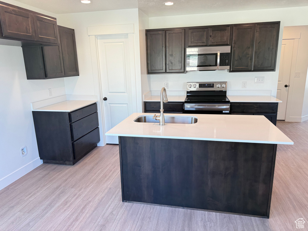 Kitchen featuring stainless steel appliances, a sink, baseboards, light countertops, and recessed lighting