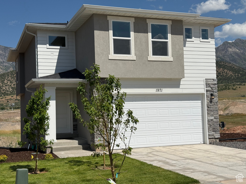 View of front facade featuring driveway, a garage, a mountain view, entry steps, and stucco siding