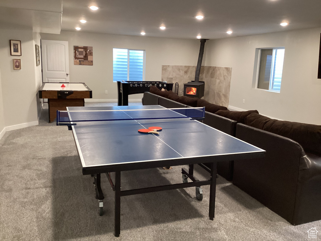 Rec room featuring a wood stove, light colored carpet, and a wealth of natural light