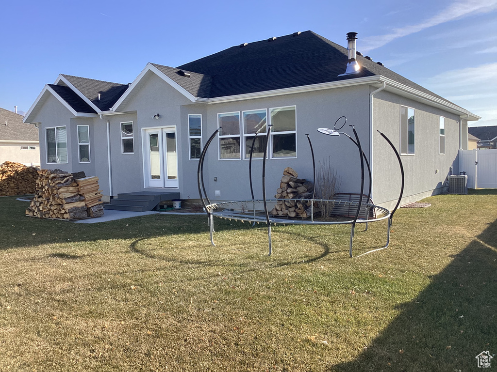 Rear view of property featuring a lawn and central AC