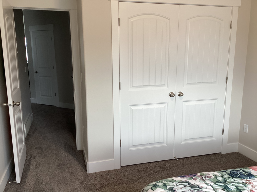 Unfurnished bedroom featuring a closet and dark colored carpet