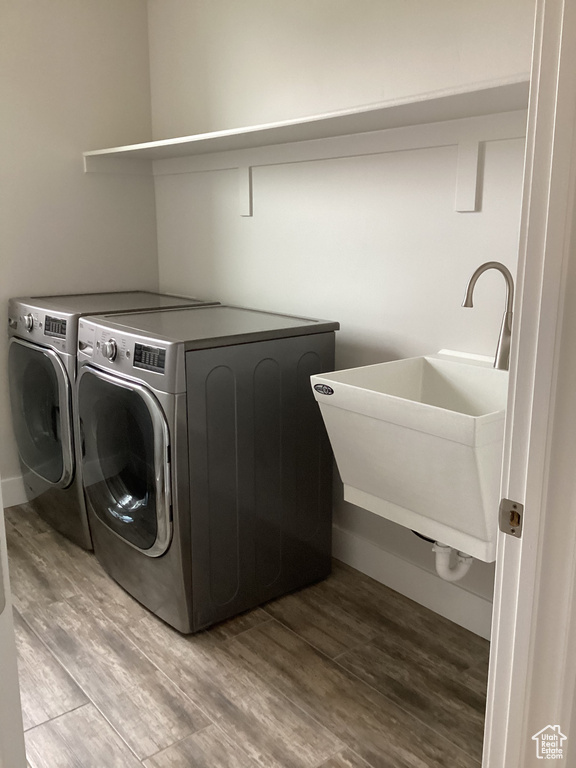 Clothes washing area featuring sink, separate washer and dryer, and light hardwood / wood-style flooring