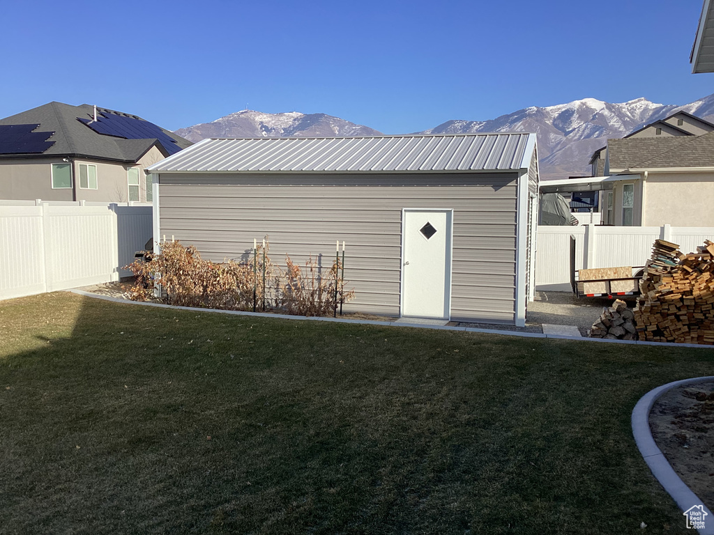 Rear view of house featuring a mountain view, a yard, and an outdoor structure