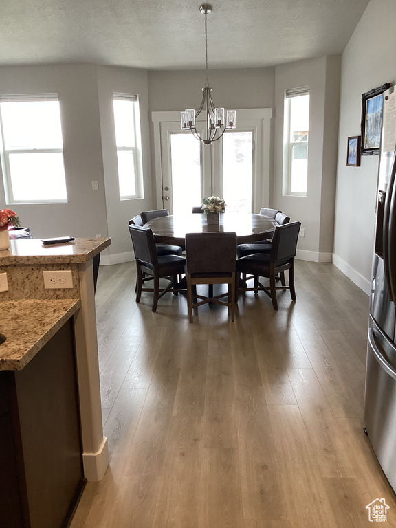 Dining room featuring a notable chandelier, wood-type flooring, and a textured ceiling
