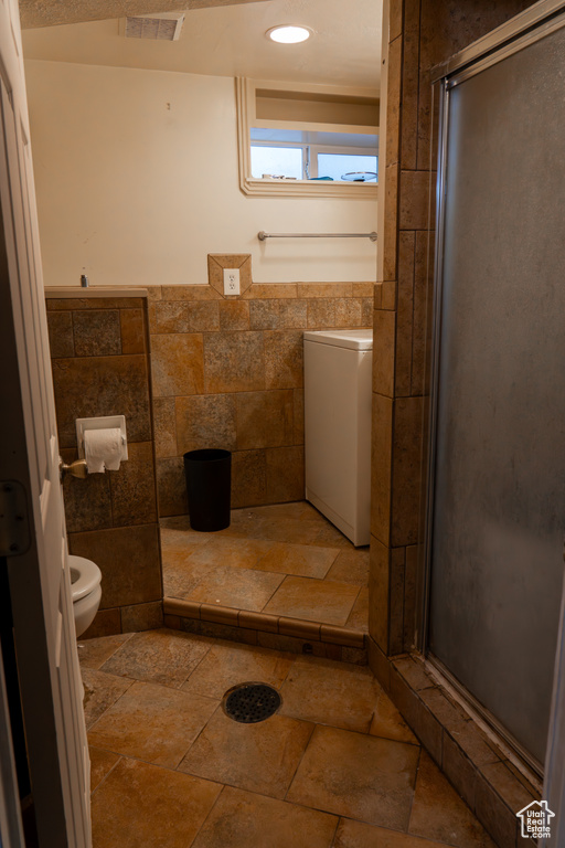 Bathroom with toilet, tile walls, and walk in shower