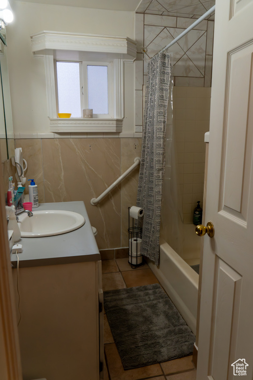 Bathroom with shower / tub combo with curtain, vanity, tile walls, and tile patterned floors