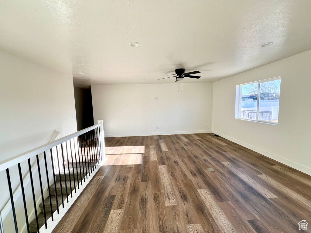 Spare room featuring a textured ceiling, dark wood-type flooring, and ceiling fan