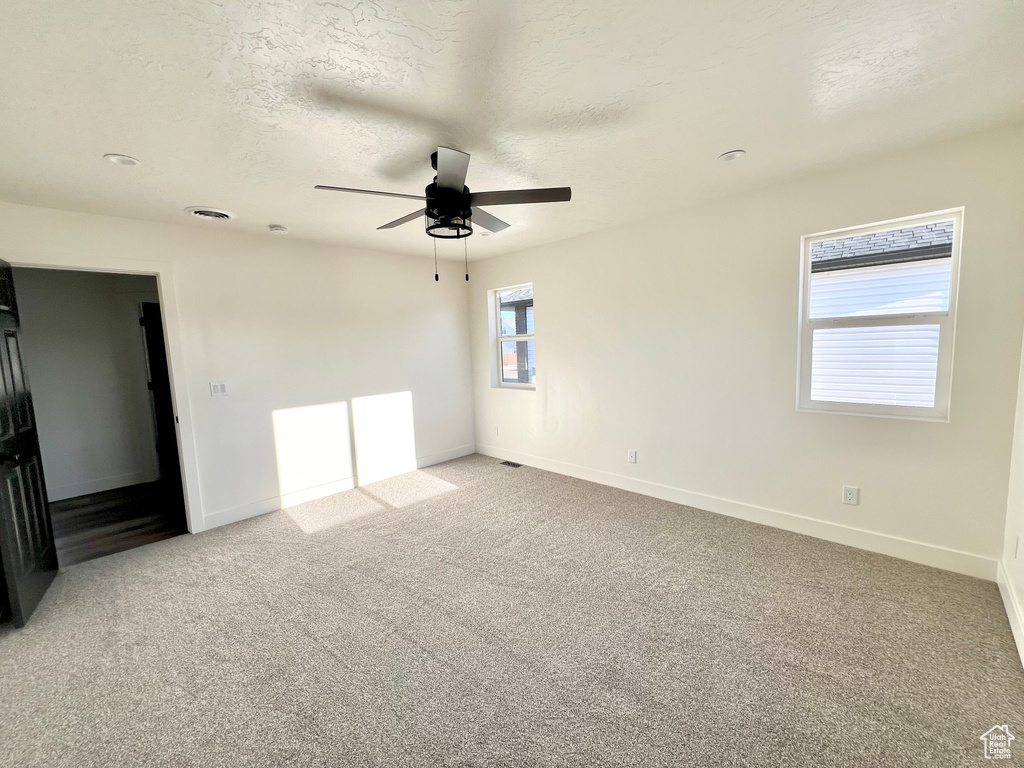 Unfurnished bedroom with light carpet, ceiling fan, and a textured ceiling