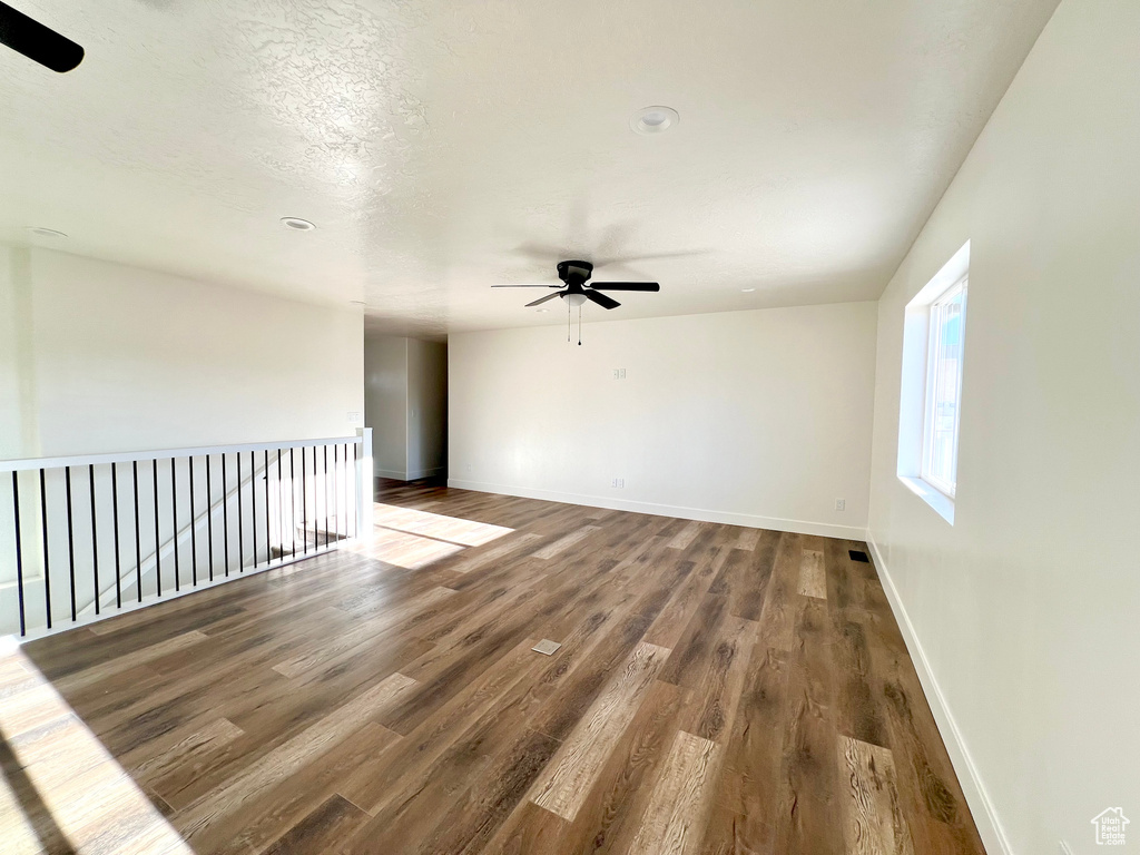 Empty room featuring ceiling fan, a textured ceiling, and hardwood / wood-style floors