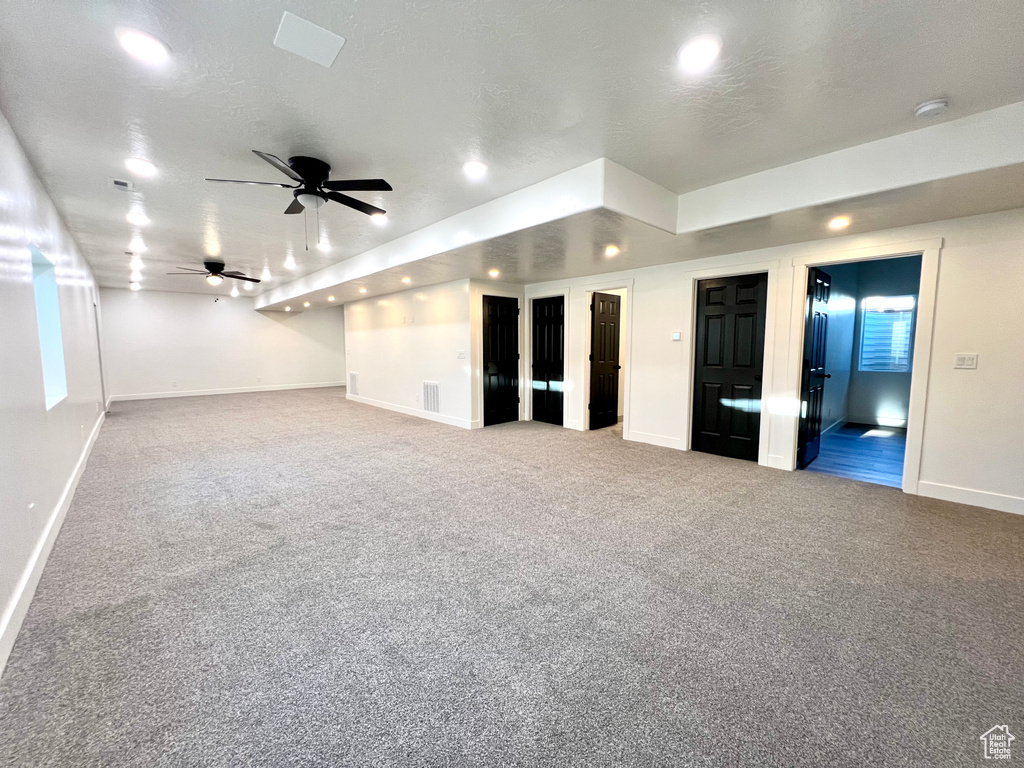 Carpeted empty room with ceiling fan and a textured ceiling