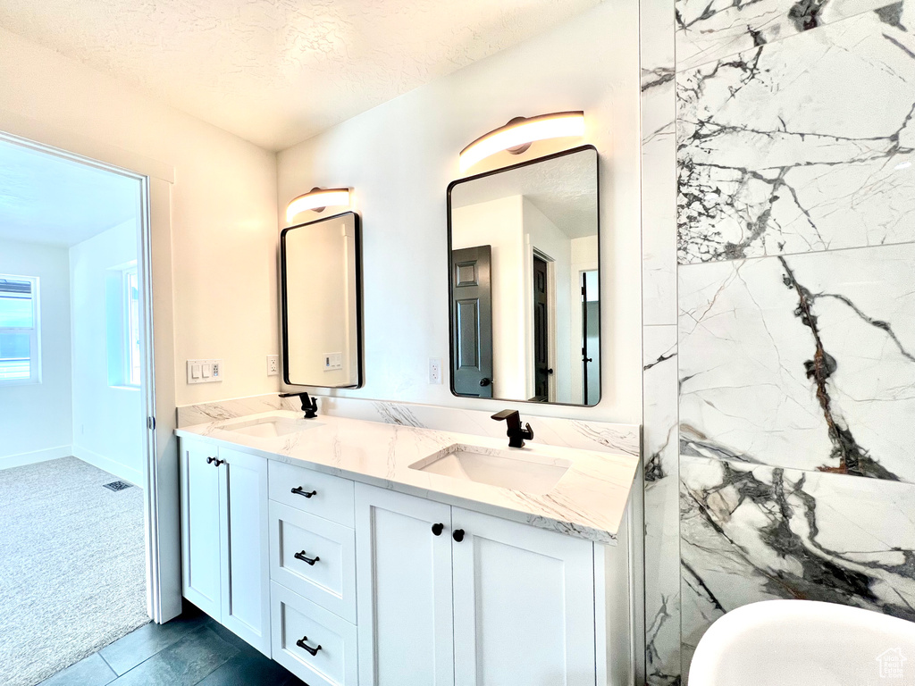 Bathroom with a bath, a textured ceiling, and vanity