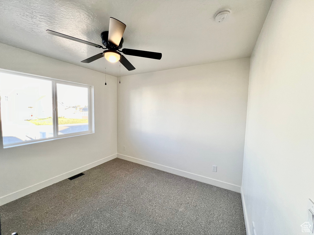 Empty room featuring ceiling fan and carpet floors
