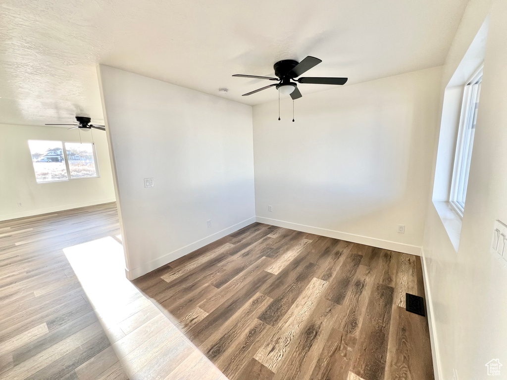 Empty room with ceiling fan and dark hardwood / wood-style floors