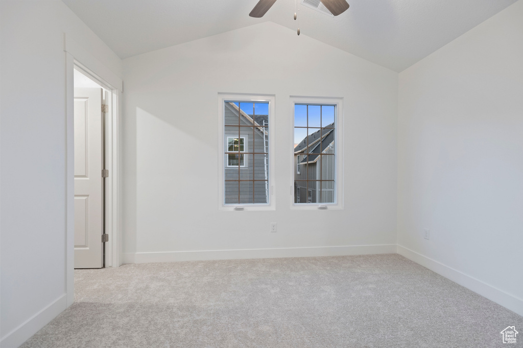 Spare room featuring carpet floors, a ceiling fan, vaulted ceiling, and baseboards