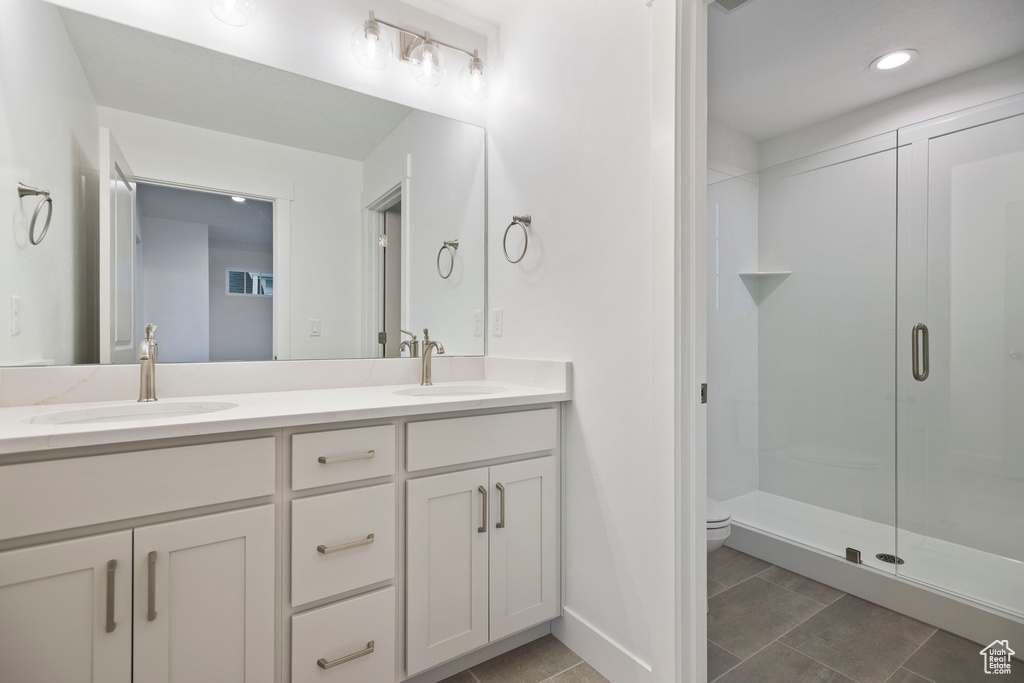 Full bath with a shower stall, double vanity, toilet, tile patterned floors, and recessed lighting