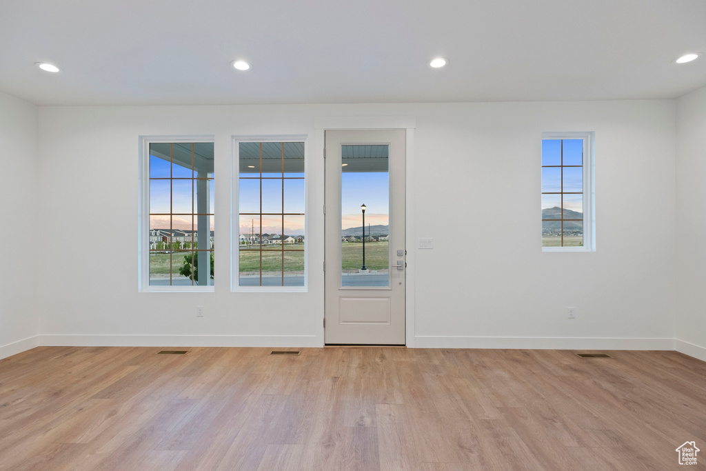 Spare room featuring plenty of natural light, light wood-style flooring, baseboards, and recessed lighting