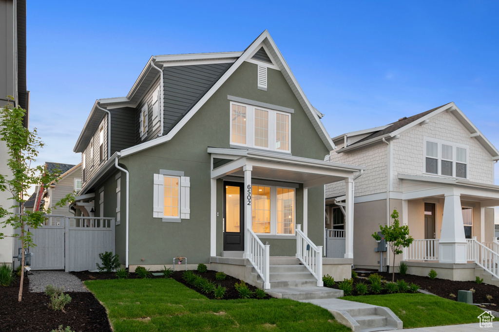 View of front of home with covered porch, stucco siding, and a front lawn