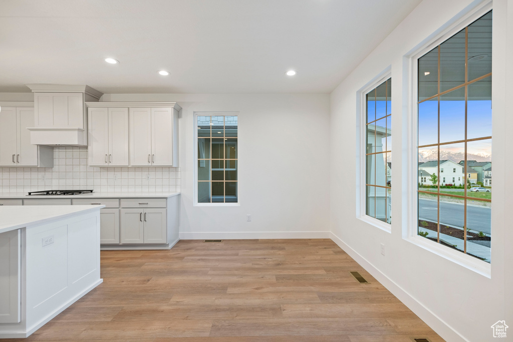 Kitchen featuring decorative backsplash, light countertops, baseboards, white cabinets, and recessed lighting