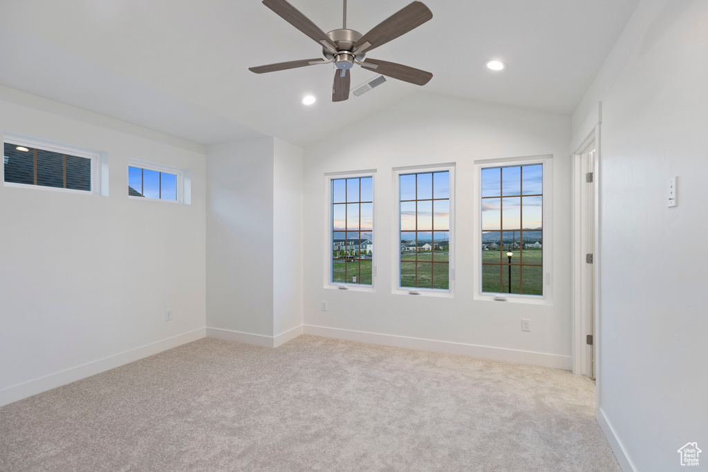 Unfurnished room with light colored carpet, ceiling fan, vaulted ceiling, baseboards, and recessed lighting