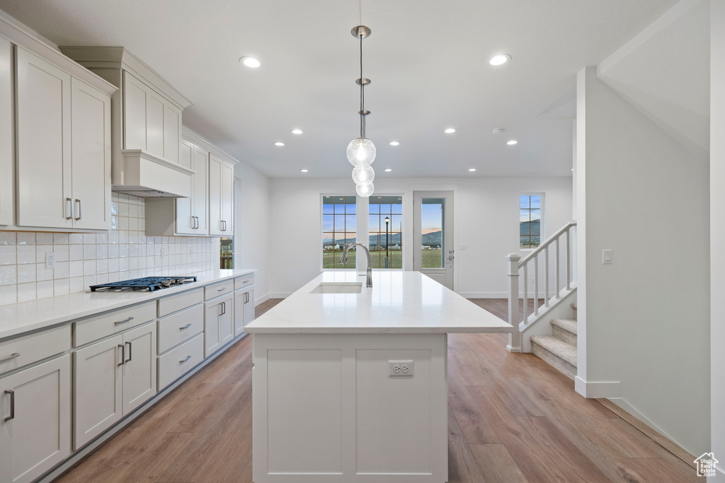 Kitchen with a sink, light wood-style floors, decorative backsplash, stainless steel gas cooktop, and recessed lighting
