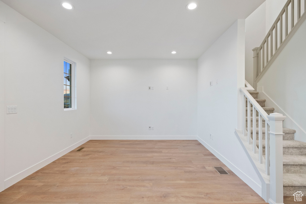Spare room with recessed lighting, stairs, light wood-type flooring, and baseboards