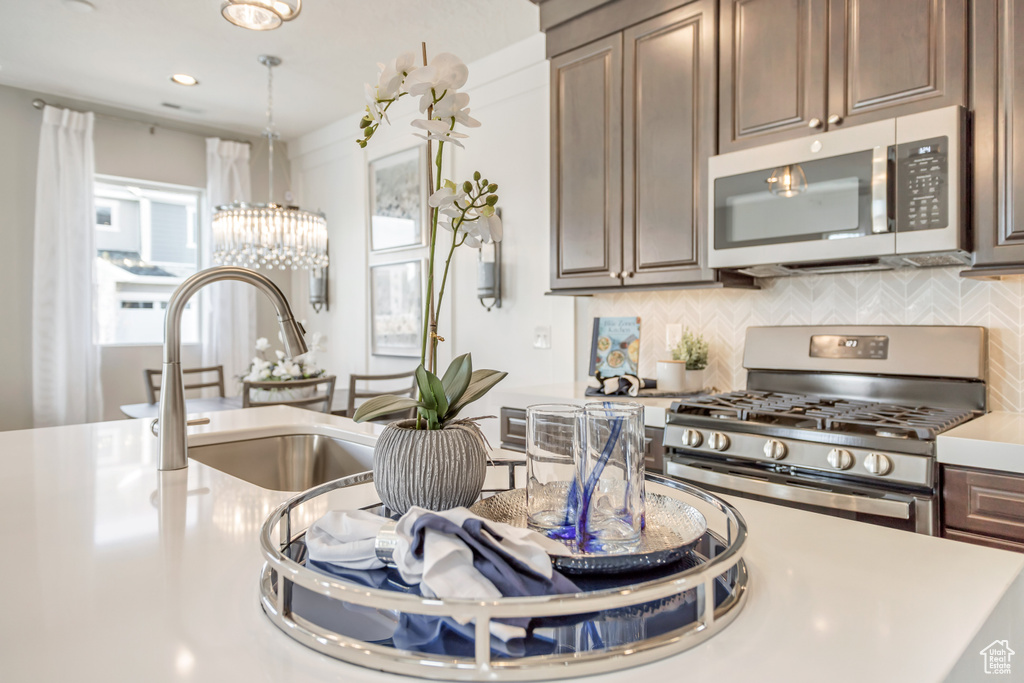Kitchen featuring appliances with stainless steel finishes, dark brown cabinets, sink, and backsplash